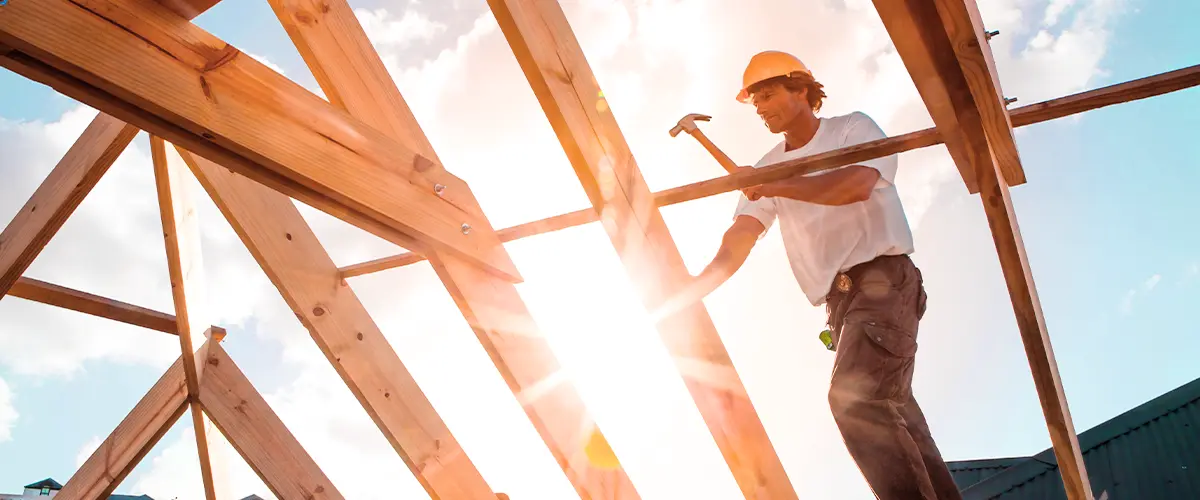 Worker building a stick frame roof with wooden beams