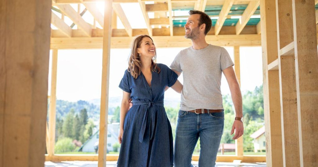 The same couple as in the previous image, captured from a slightly different angle, smiling and walking together through the construction site.