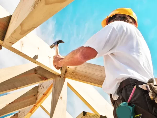 Low-angle view of man hammering on a stick frame roof